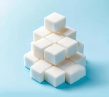 White sugar cubes arranged in a pyramid on a light blue background create a striking visual display showcasing simplicity and texture photo
