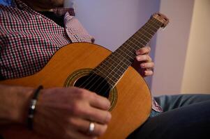Man strumming a classical guitar in a casual indoor setting photo
