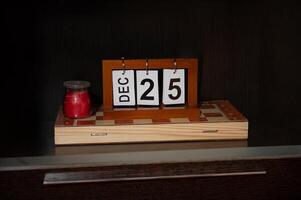 Wooden block calendar with December 25th displayed next to red candle photo