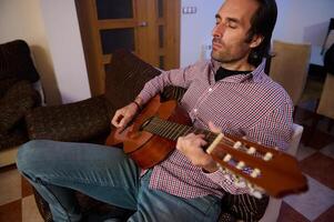 Man relaxing with acoustic guitar in a cozy living room setting photo