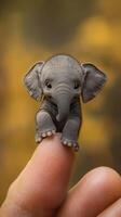 A tiny elephant balances gracefully on the tip of a finger amidst a colorful autumn backdrop photo