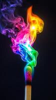 Colorful smoke swirls gracefully from a lit match against a dark background in a mesmerizing display photo