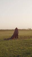 Figure wrapped in flowing fabric in open field video
