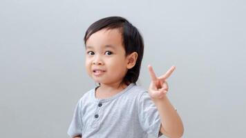 asian boy showing up two fingers, the peace symbol. photo