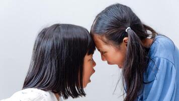 Angry little Asian girl shouting fighting with each other isolated over grey background, sisters screaming and Hate, Mental health and Stress. photo