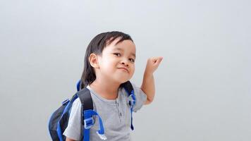 Cute Asian child student with backpack pointing with finger, confident gesture looking serious photo
