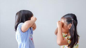 Sad offended two little girl sit hide face in hands feel disappointed after fight, hurt upset small preschooler child suffer from discrimination at school, loner, outcast concept. photo