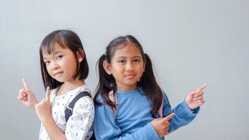 Photo of two happy excited children look point finger empty space wear backpack isolated on light color background