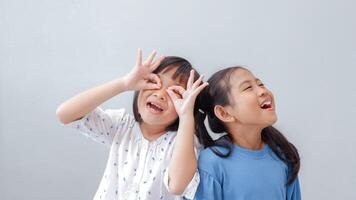 happiness friendship concept. Portrait of inquisitive nosy little girls looking through fingers shaped like binoculars and expressing cheerful. photo