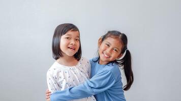 Studio portrait of Asian children on a light background, two children hugging as a best friend and smiling to the camera. photo
