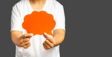 Close-up of hand holding a red speech bubble standing against a gray background photo