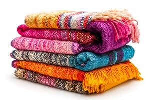 Stack of colorful knitted blankets with tassels on white background photo