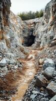 Muddy path leading into dark abandoned mine in rocky quarry landscape photo