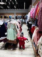 Child examining clothing racks in a colorful and vibrant apparel store photo