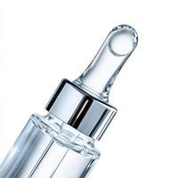 Clear glass dropper bottle with shiny silver cap and pipette for cosmetic serum photo