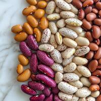 Colorful assortment of dried beans arranged on a marble surface for culinary inspiration and recipe ideas photo