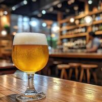 Golden craft beer served in a glass on a wooden table in a cozy bar during evening hours photo