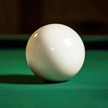 White billiard ball resting on a green felt table after a shot during a game in a dimly lit room photo