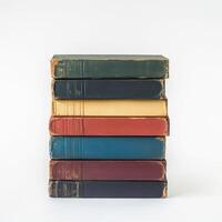 Vintage stacked books on a white background showcasing worn covers and varying colors photo