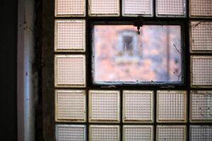 Close-up of a desolate and dirty factory window made of glass bricks photo
