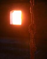 Torn rope hanging in front of bright sunny window photo