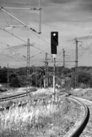 Black and white shot of rails in Germany with many power lines, signals and switches photo