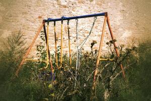 Abandoned swing in thistles in scary, grungy image photo