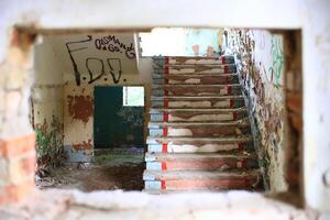 Looking through hole in the wall to abandoned staircase photo