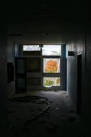 Hallway of abandoned building with a shattered glass door photo