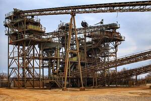 Grungy shot of gravel quarry, with rusty metal frames and and conveyor belts photo