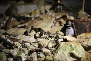 Underground mine scene with scattered tools and lanterns among rocks and debris photo
