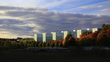 University buildings of Stockholm with glass facades surrounded by autumn foliage under a cloudy sky photo