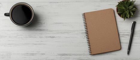 Top view of a workspace with coffee, notebook, pen, and succulent photo