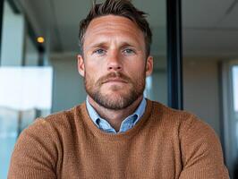 Portrait of a man with blue eyes and a beard wearing a brown sweater photo