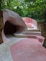 Abstract pink and beige concrete structure in a forest setting photo