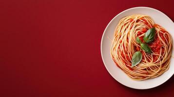 Overhead view of spaghetti with tomato sauce and basil on a red background photo