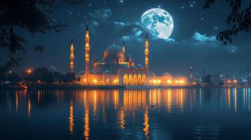 Majestic mosque illuminated at night under a full moon reflecting in water photo