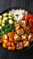 Grilled chicken bowl with vegetables and rice served in a black bowl photo