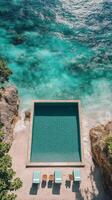 Beautiful cliffside swimming pool overlooking the ocean with clear blue water in a serene location photo