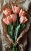 Beautiful bouquet of pink tulips wrapped in kraft paper on rustic wooden table photo
