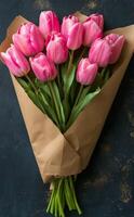 Beautiful bouquet of pink tulips wrapped in kraft paper on rustic wooden table photo