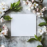 Blank card surrounded by delicate pink flowers and green leaves on rustic wooden background photo