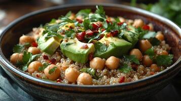 Bowl filled with quinoa, chickpeas, avocado, and fresh herbs set on a rustic table photo