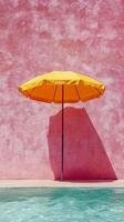 Bright yellow umbrella beside a serene swimming pool against a pink wall photo