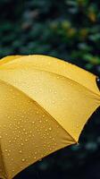 Bright yellow umbrella covered in raindrops during a rainy day photo