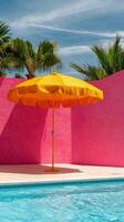 Bright yellow umbrella beside a serene swimming pool against a pink wall photo