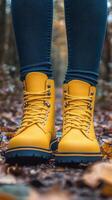 Bright yellow rain boots stand on a wet road surrounded by autumn foliage photo