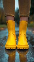 Bright yellow rain boots stand on a wet road surrounded by autumn foliage photo