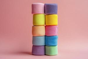 Colorful stacked sponges arranged in a gradient pattern on a soft pink background photo