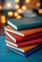 Colorful stacked notebooks on blue surface with sparkling lights in the background during evening hours photo